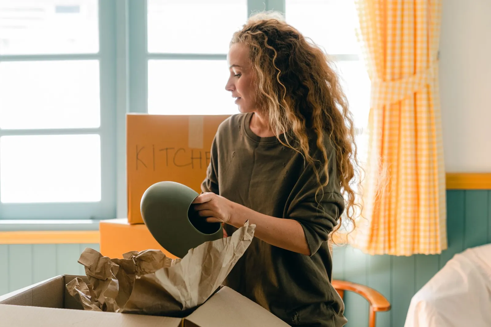 Une femme déballe une céramique chez elle, près de la fenêtre