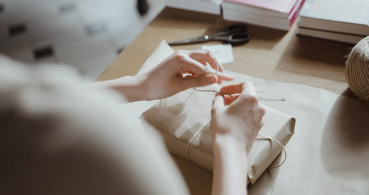 Des mains déposent un objet emballé dans un carton